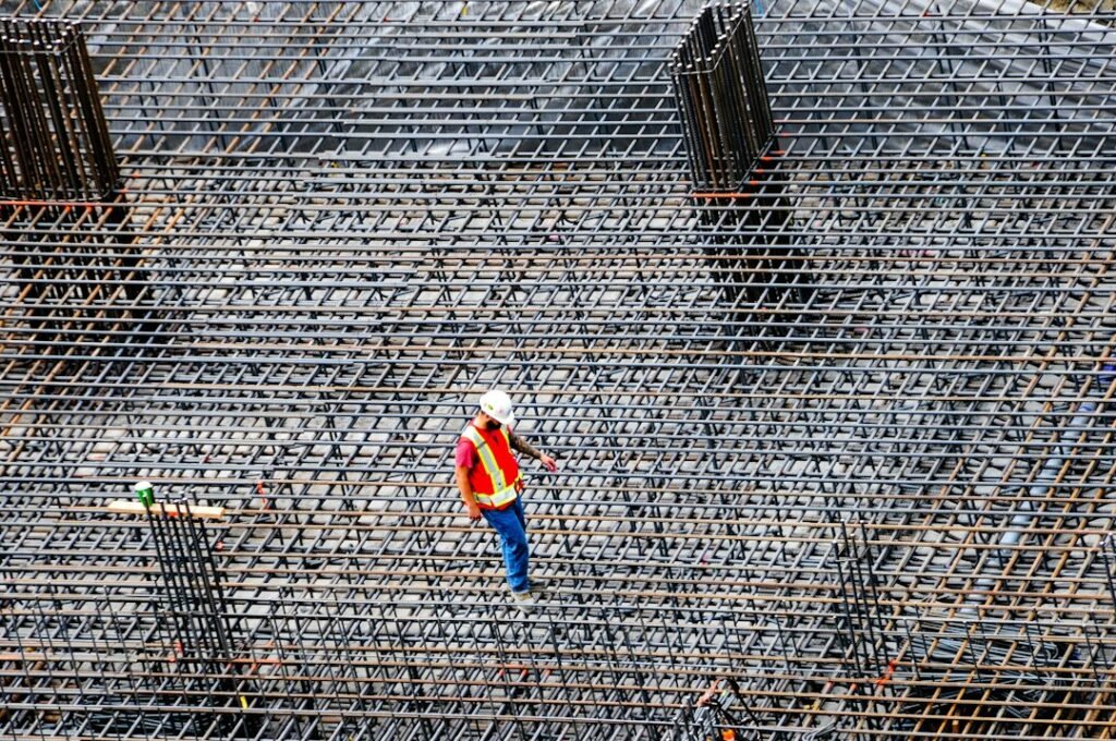 Construction worker balancing on rebar at a building site.